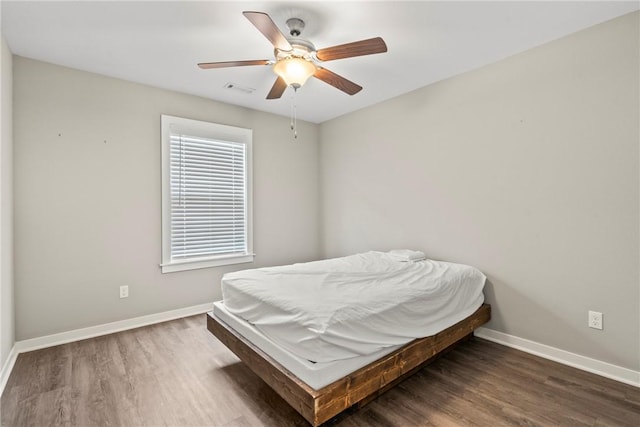 bedroom featuring baseboards, ceiling fan, wood finished floors, and visible vents