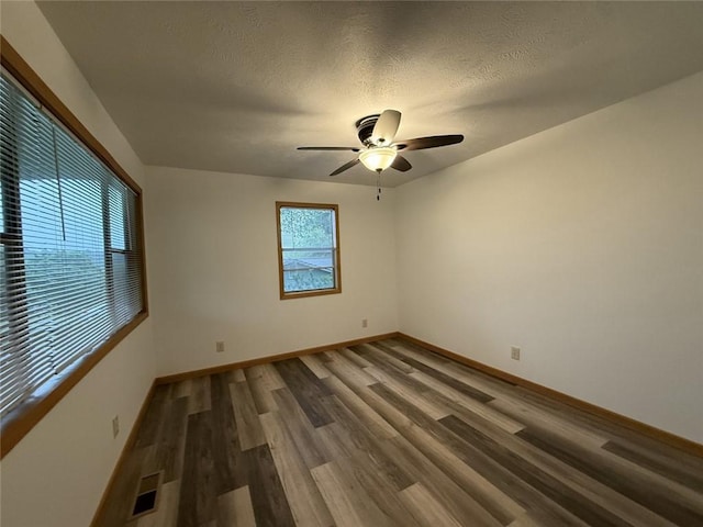 unfurnished room featuring a textured ceiling, ceiling fan, baseboards, and wood finished floors