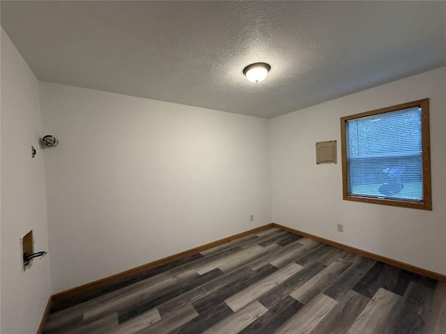 spare room featuring a textured ceiling, baseboards, and wood finished floors