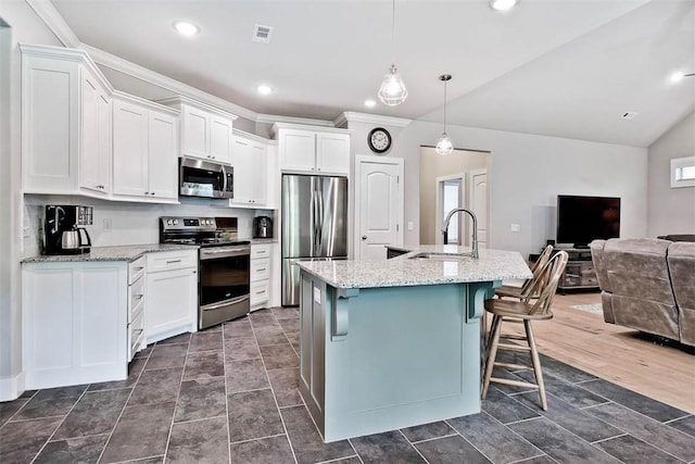 kitchen featuring visible vents, open floor plan, white cabinets, a sink, and stainless steel appliances