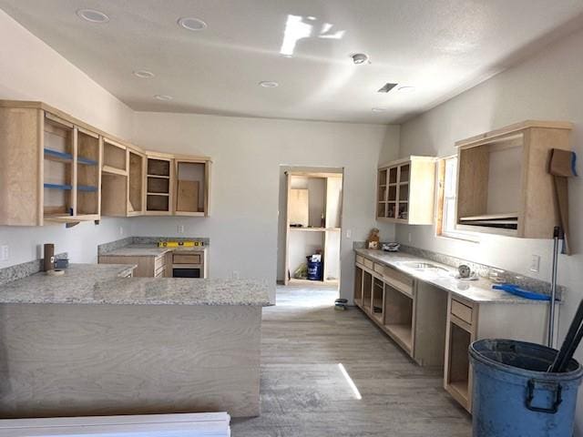 kitchen with open shelves, light stone countertops, and light wood finished floors