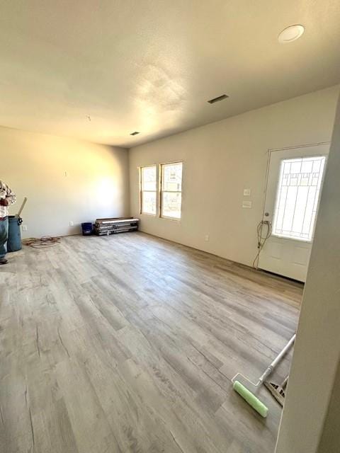unfurnished living room featuring visible vents and wood finished floors