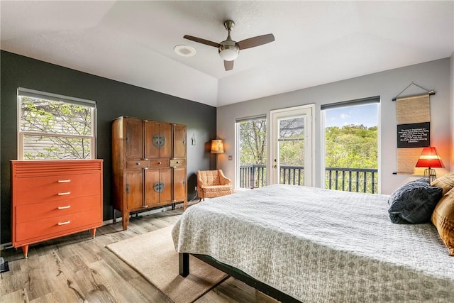 bedroom featuring a ceiling fan, light wood finished floors, multiple windows, and access to exterior