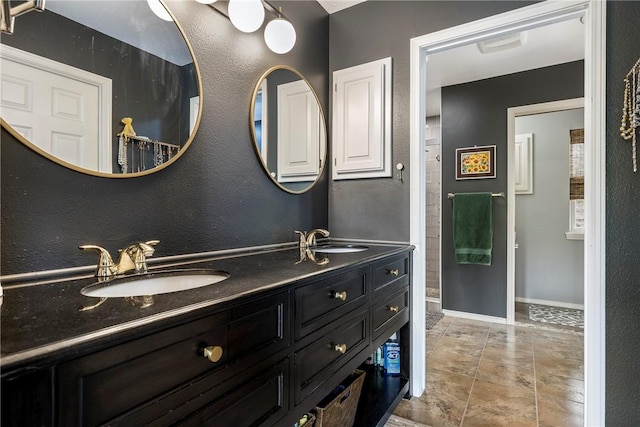 full bathroom with baseboards, a sink, a textured wall, and double vanity