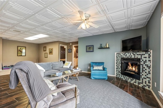 living area featuring an ornate ceiling, baseboards, wood tiled floor, and a tile fireplace