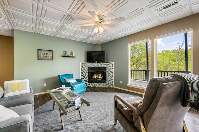 57 Dunsford Dr, Bella Vista, AR 72715 - living area featuring baseboards, plenty of natural light, a ceiling fan, a tile fireplace, and an ornate ceiling