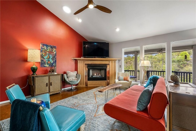 living area with recessed lighting, a ceiling fan, vaulted ceiling, and a lit fireplace