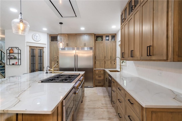 13248 N Old Wire Rd, Rogers, AR 72756 - kitchen featuring brown cabinetry, built in appliances, a sink, light wood-type flooring, and a large island