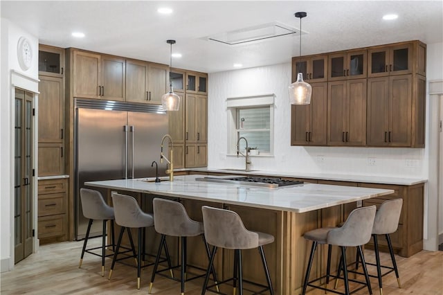 13248 N Old Wire Rd, Rogers, AR 72756 - kitchen with a sink, stainless steel appliances, light wood-style floors, a kitchen island with sink, and glass insert cabinets