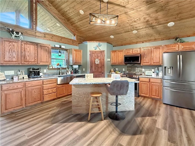 kitchen featuring high vaulted ceiling, appliances with stainless steel finishes, a sink, and light wood-style flooring