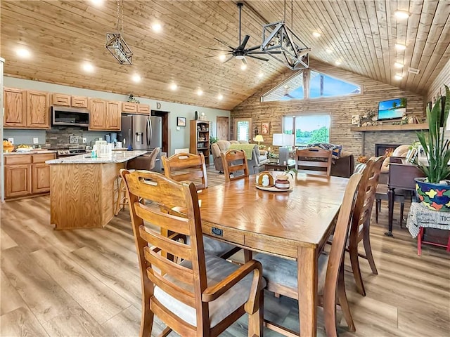 dining room featuring ceiling fan, light wood finished floors, a fireplace, high vaulted ceiling, and wooden ceiling
