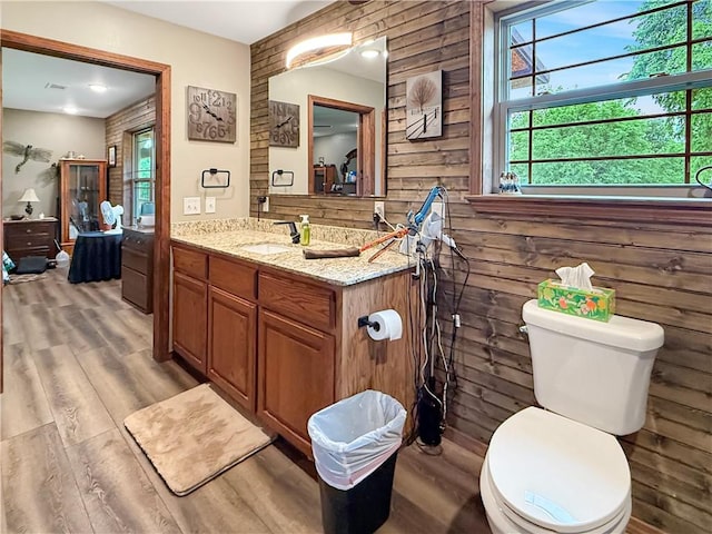 bathroom featuring toilet, wood walls, wood finished floors, and vanity