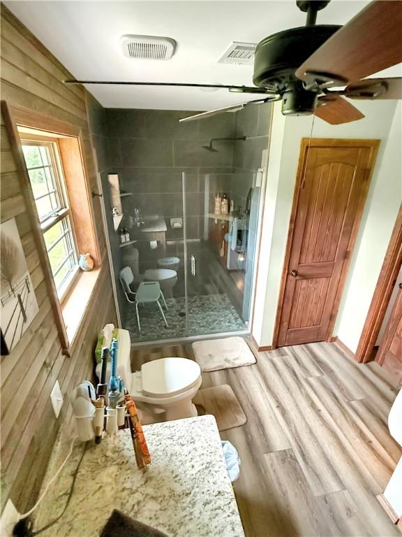 full bath featuring toilet, a ceiling fan, wood finished floors, visible vents, and a stall shower