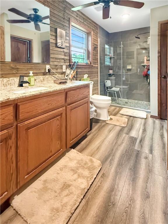 bathroom featuring vanity, toilet, a ceiling fan, wood finished floors, and a stall shower