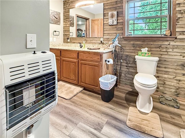 bathroom featuring vanity, heating unit, wood finished floors, and toilet