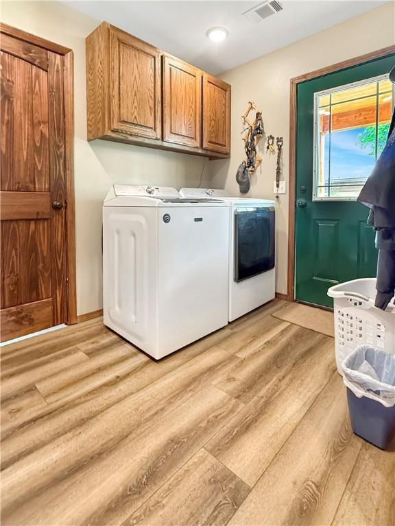 laundry room featuring visible vents, light wood finished floors, independent washer and dryer, and cabinet space