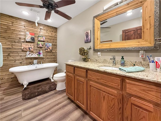 full bathroom featuring ceiling fan, visible vents, a freestanding bath, wood finished floors, and vanity