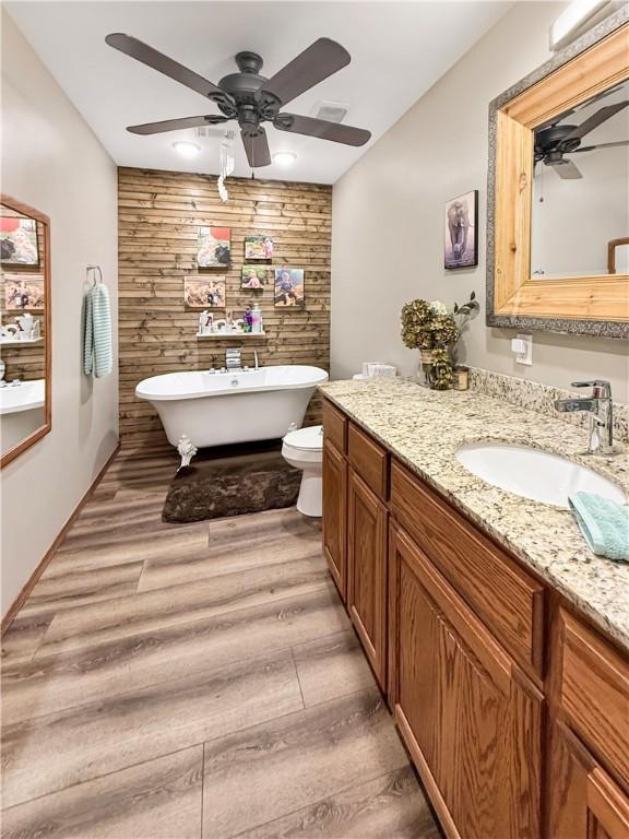 bathroom featuring vanity, a soaking tub, a ceiling fan, and wood finished floors