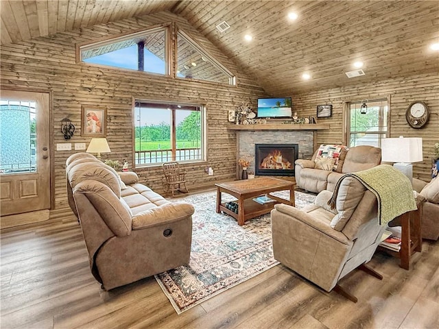 living room featuring high vaulted ceiling, wood ceiling, a stone fireplace, and wood finished floors