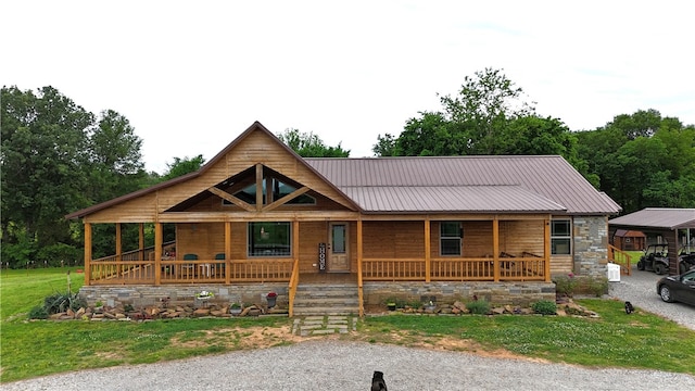 view of front facade with a front lawn, covered porch, stone siding, and metal roof