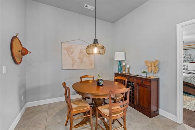 dining room featuring visible vents, baseboards, lofted ceiling, and light tile patterned floors