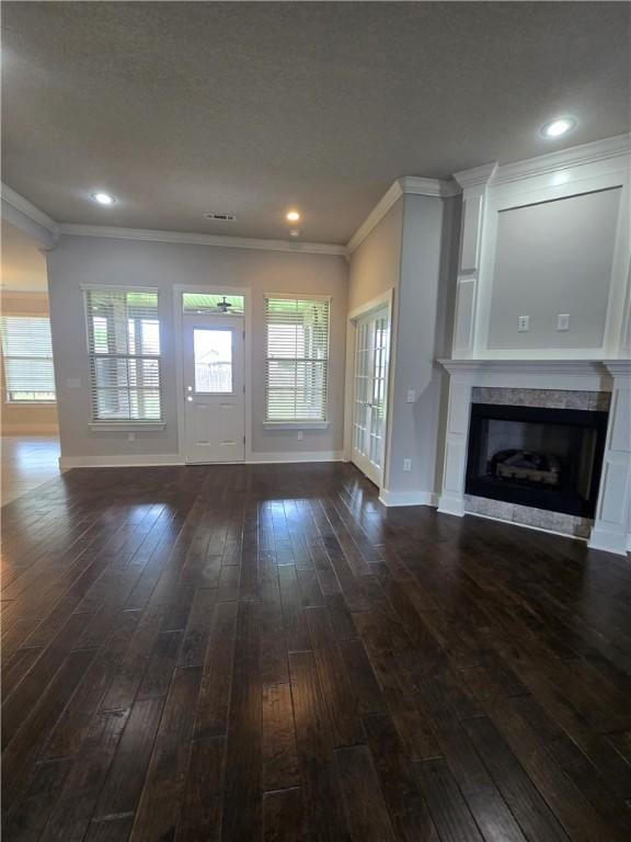 unfurnished living room featuring visible vents, ornamental molding, a fireplace, baseboards, and dark wood-type flooring