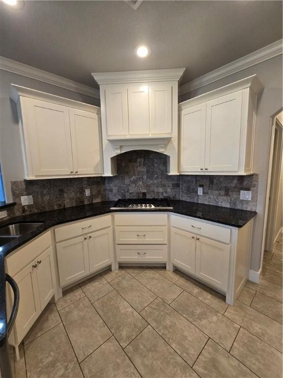 kitchen featuring a sink, white cabinetry, gas stovetop, tasteful backsplash, and ornamental molding
