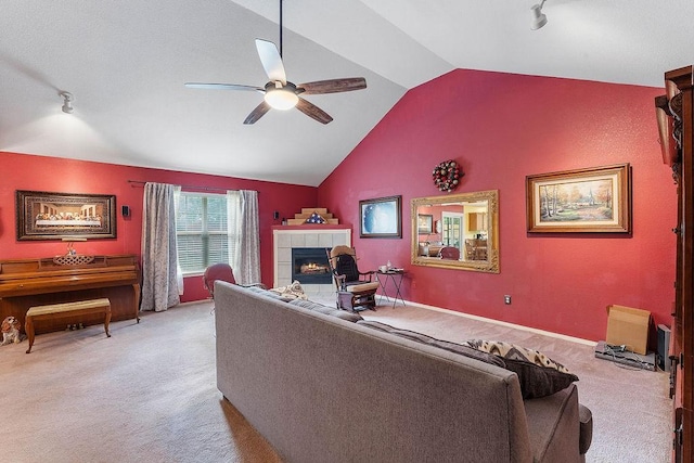 living room with ceiling fan, track lighting, light carpet, a tiled fireplace, and vaulted ceiling