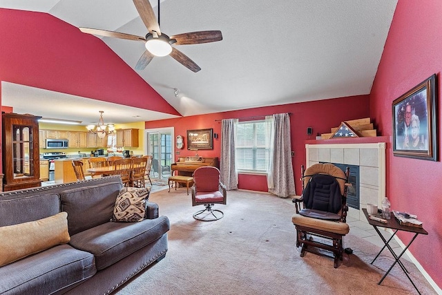 living room featuring high vaulted ceiling, light carpet, a tiled fireplace, and ceiling fan with notable chandelier