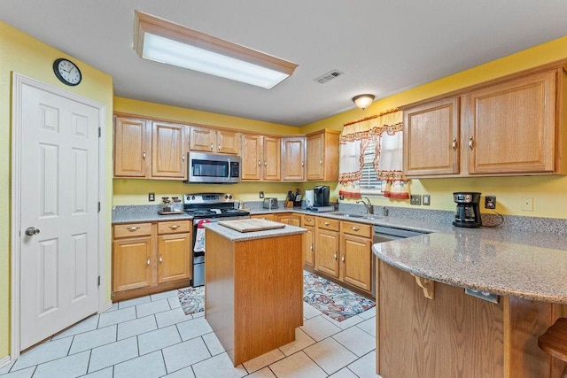 kitchen with light tile patterned flooring, a center island, stainless steel appliances, a peninsula, and visible vents