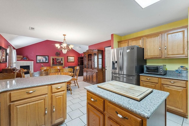 kitchen with light tile patterned flooring, stainless steel fridge with ice dispenser, open floor plan, a toaster, and visible vents