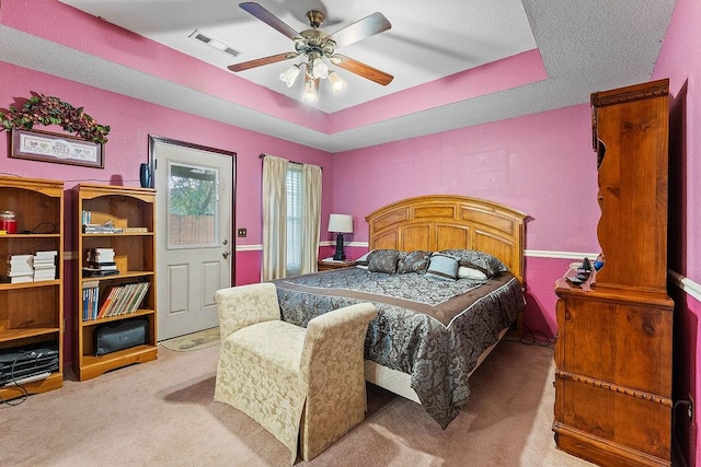 bedroom featuring carpet floors, a ceiling fan, a raised ceiling, and visible vents