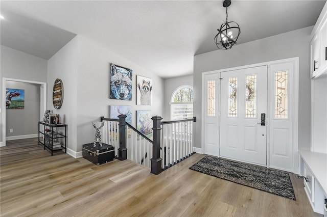 foyer with baseboards, light wood-style flooring, and a chandelier