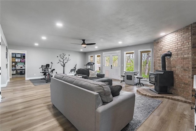 living room featuring ceiling fan, light wood-type flooring, a wood stove, and recessed lighting