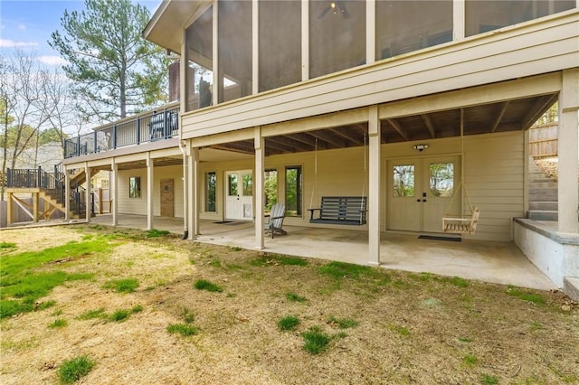 back of property featuring french doors, a deck, a sunroom, a patio area, and stairs
