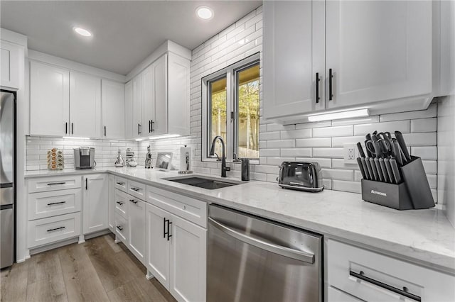 kitchen with light stone counters, a sink, white cabinetry, tasteful backsplash, and stainless steel dishwasher