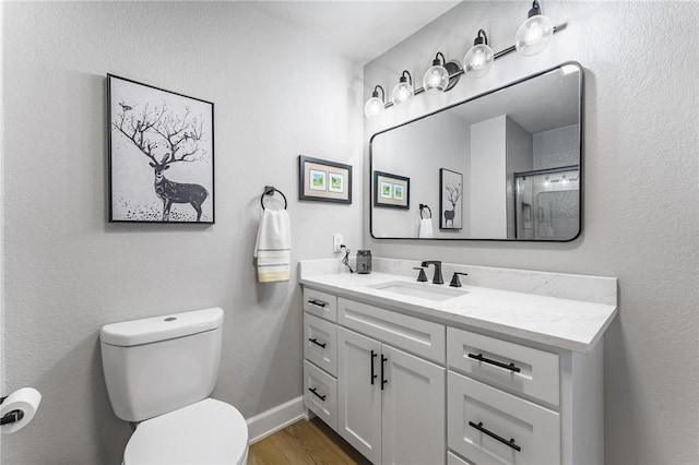 full bathroom featuring an enclosed shower, wood finished floors, vanity, baseboards, and toilet