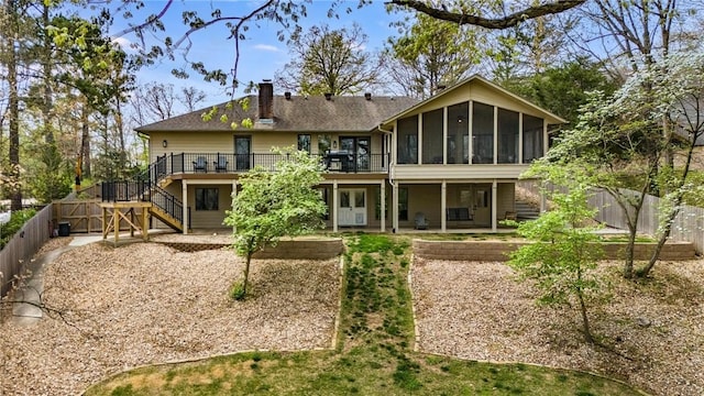 rear view of house with a sunroom, a deck, stairway, a chimney, and a patio