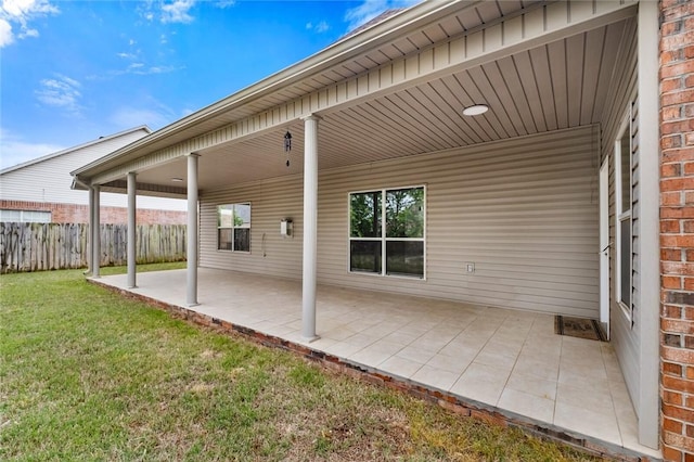 rear view of house with fence, brick siding, board and batten siding, a patio area, and a yard