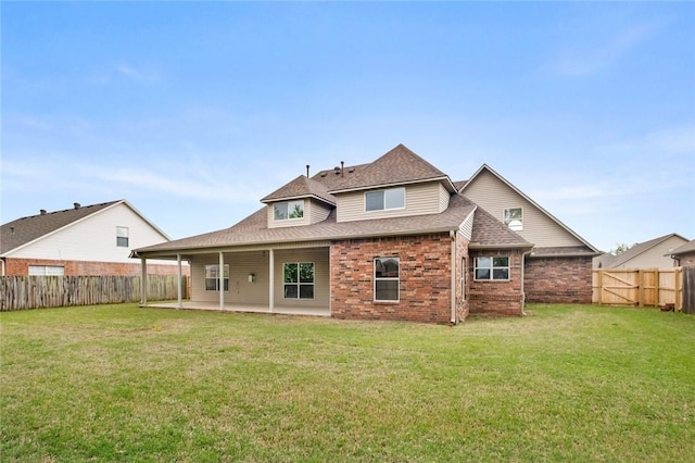 rear view of house with a fenced backyard, a yard, a patio area, and brick siding