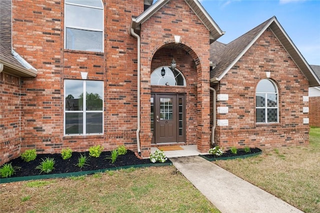 doorway to property with a lawn and brick siding