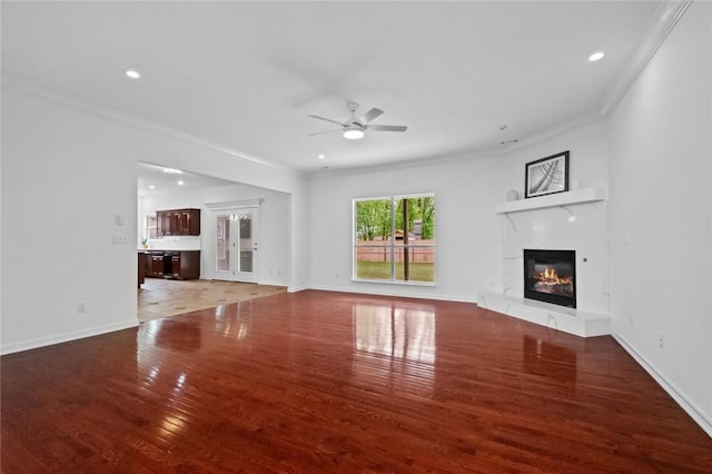 unfurnished living room with crown molding, ceiling fan, a glass covered fireplace, and light wood-type flooring