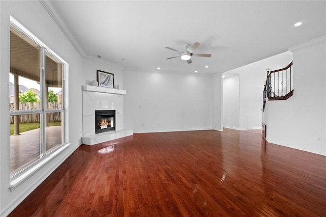 unfurnished living room featuring a glass covered fireplace, a ceiling fan, stairs, and wood finished floors