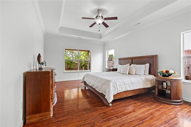 bedroom featuring crown molding, a tray ceiling, baseboards, and wood finished floors