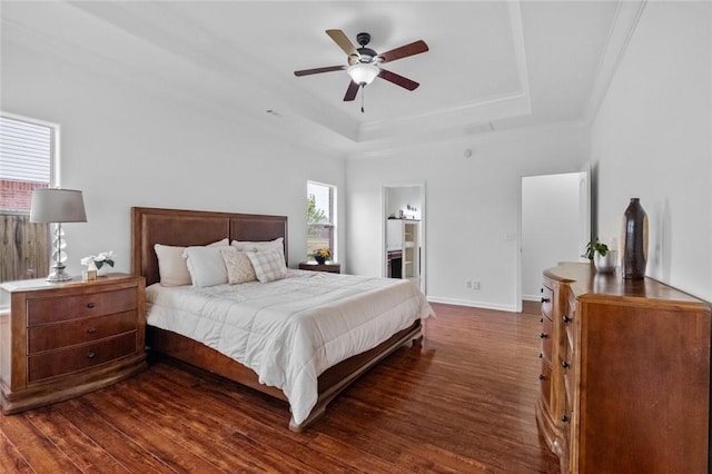 bedroom featuring baseboards, a ceiling fan, a tray ceiling, and wood finished floors