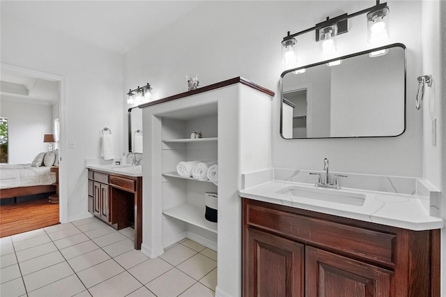 ensuite bathroom featuring connected bathroom, tile patterned floors, two vanities, and a sink