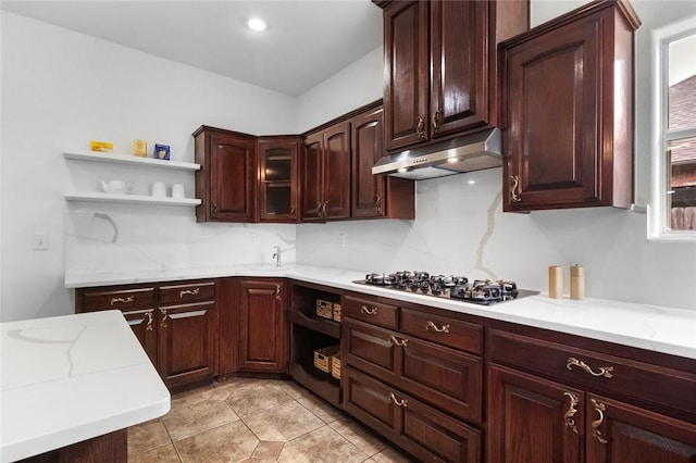kitchen featuring gas cooktop, open shelves, under cabinet range hood, and light stone counters