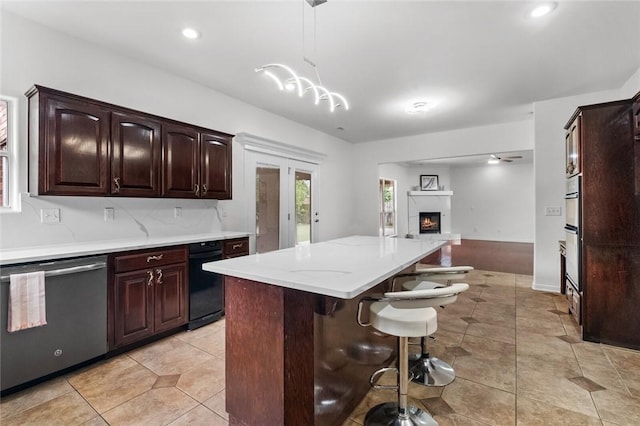 kitchen with a kitchen breakfast bar, a kitchen island, dishwasher, open floor plan, and light tile patterned flooring