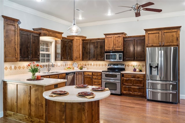 kitchen with ceiling fan, appliances with stainless steel finishes, a sink, light countertops, and ornamental molding