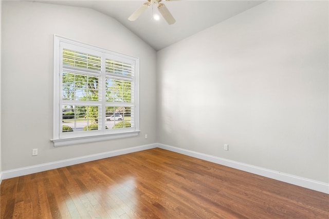 spare room with baseboards, ceiling fan, vaulted ceiling, and wood finished floors